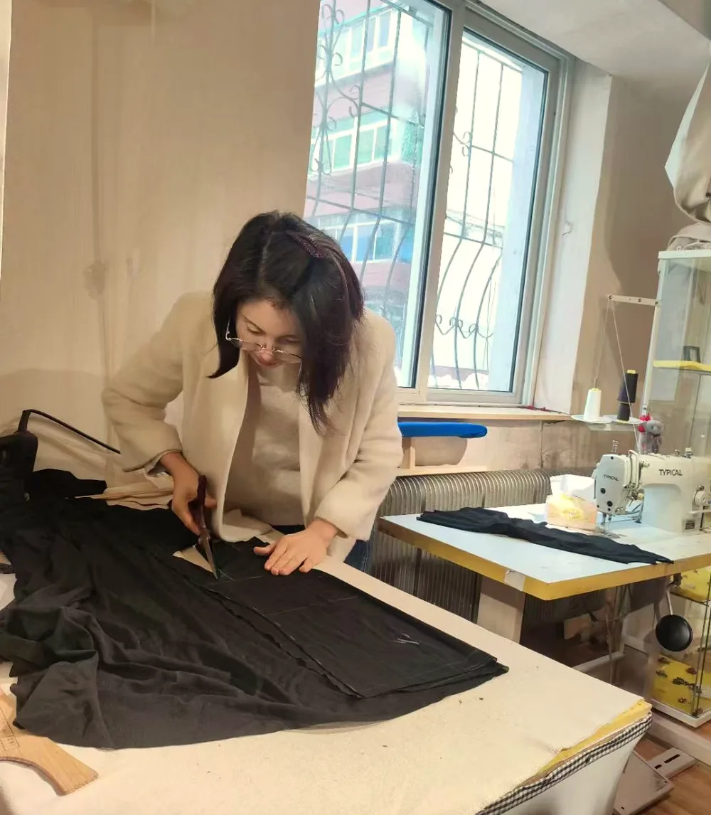 Cutting cloth at the work table in the Biying atelier