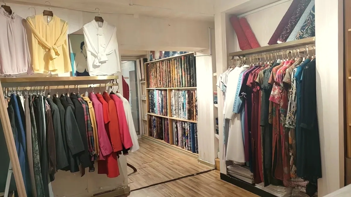 Inside the Biying shop — garment rails and the fabric wall