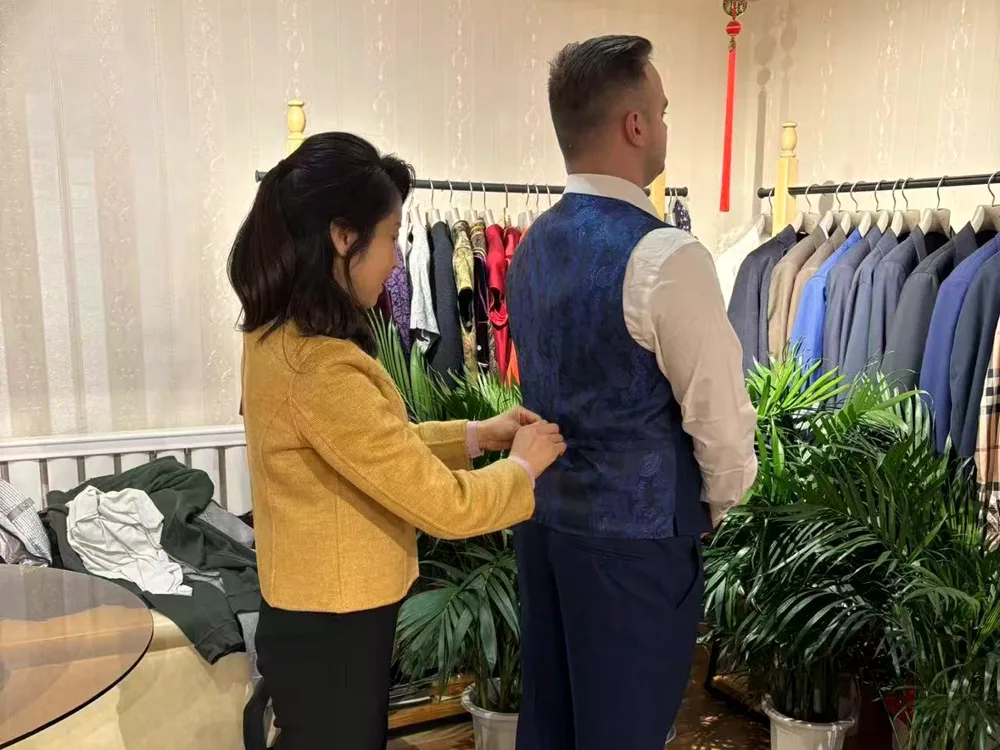 Biying adjusting a waistcoat at a fitting in the shop